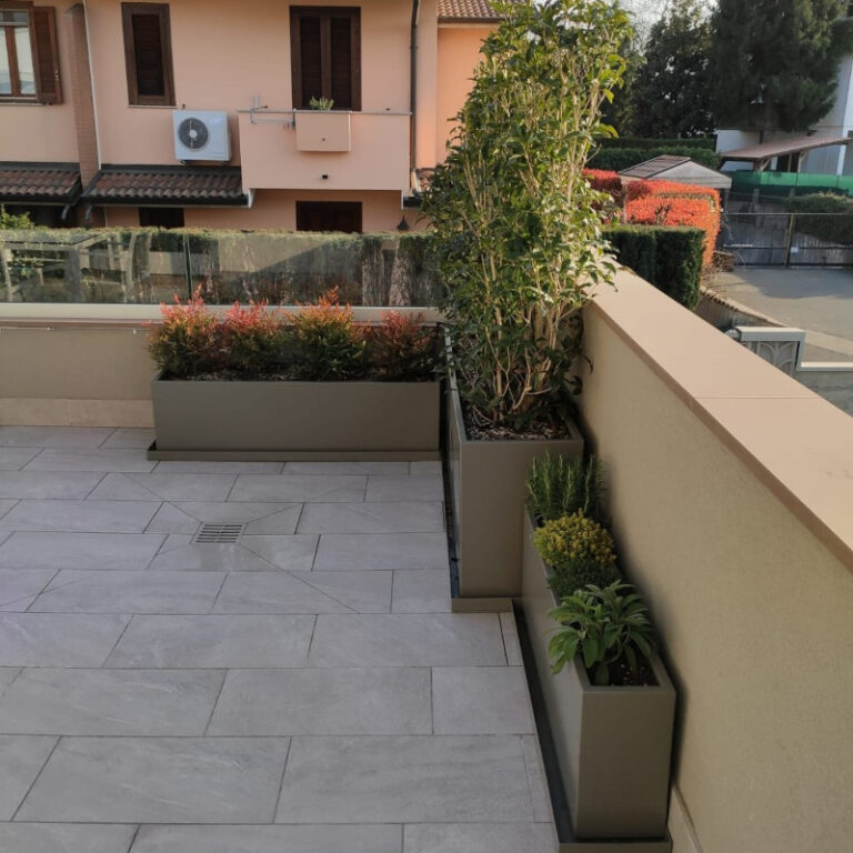 Fioriere in alluminio grigio angolari di dimensioni diverse con piante verdi collocate su terrazzo