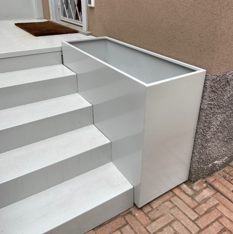 Fioriera in alluminio bianco collocata tra una scalinata e un muro