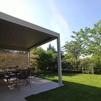 pergola in alluminio aperta sui lati addossata a casa che da' su giardino